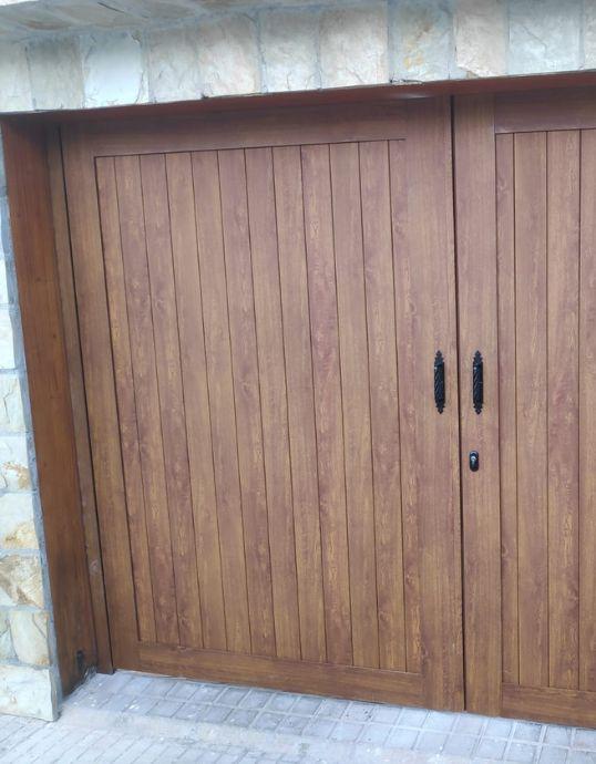 Detalle del tirador forjado en una puerta de garaje de aluminio con lamas efecto madera.