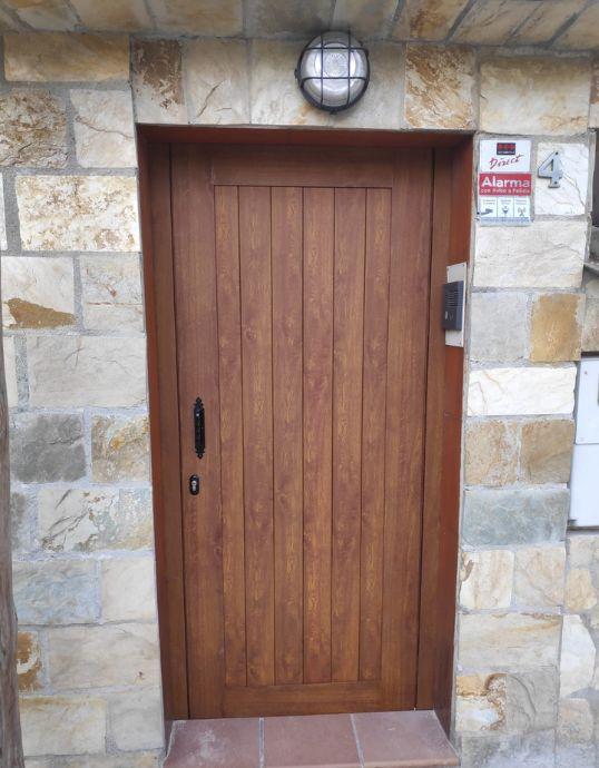 Puerta de entrada principal de aluminio imitación madera con tirador rústico negro en Casa en Vilassar de Dalt.